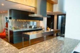Modern kitchen with stainless steel island,  black cabinets,  hard wood floor and granite countertops