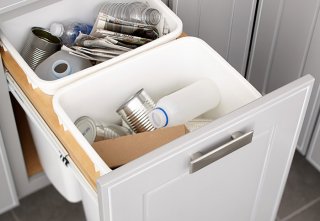 Trash cans tucked inside of a kitchen cabinet door or drawer.